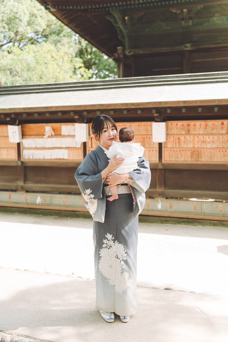 訪問着姿のお母さまが赤ちゃんを抱いて神社に立っている