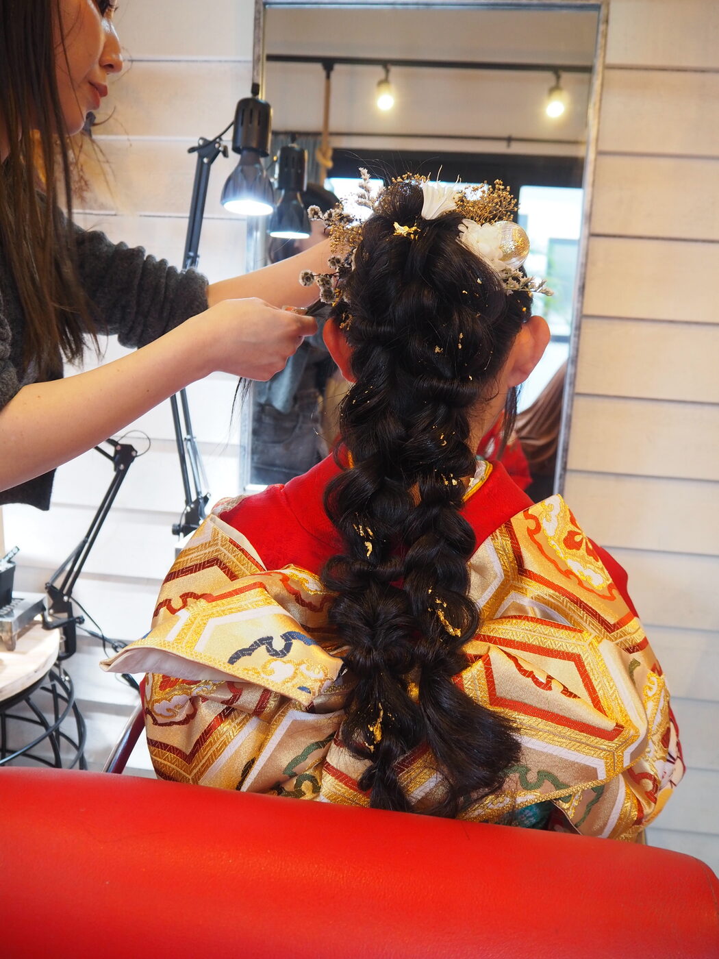 成人式の振袖ヘアセット。編み下ろしに金箔と白い髪飾りを重ねた後ろ姿
