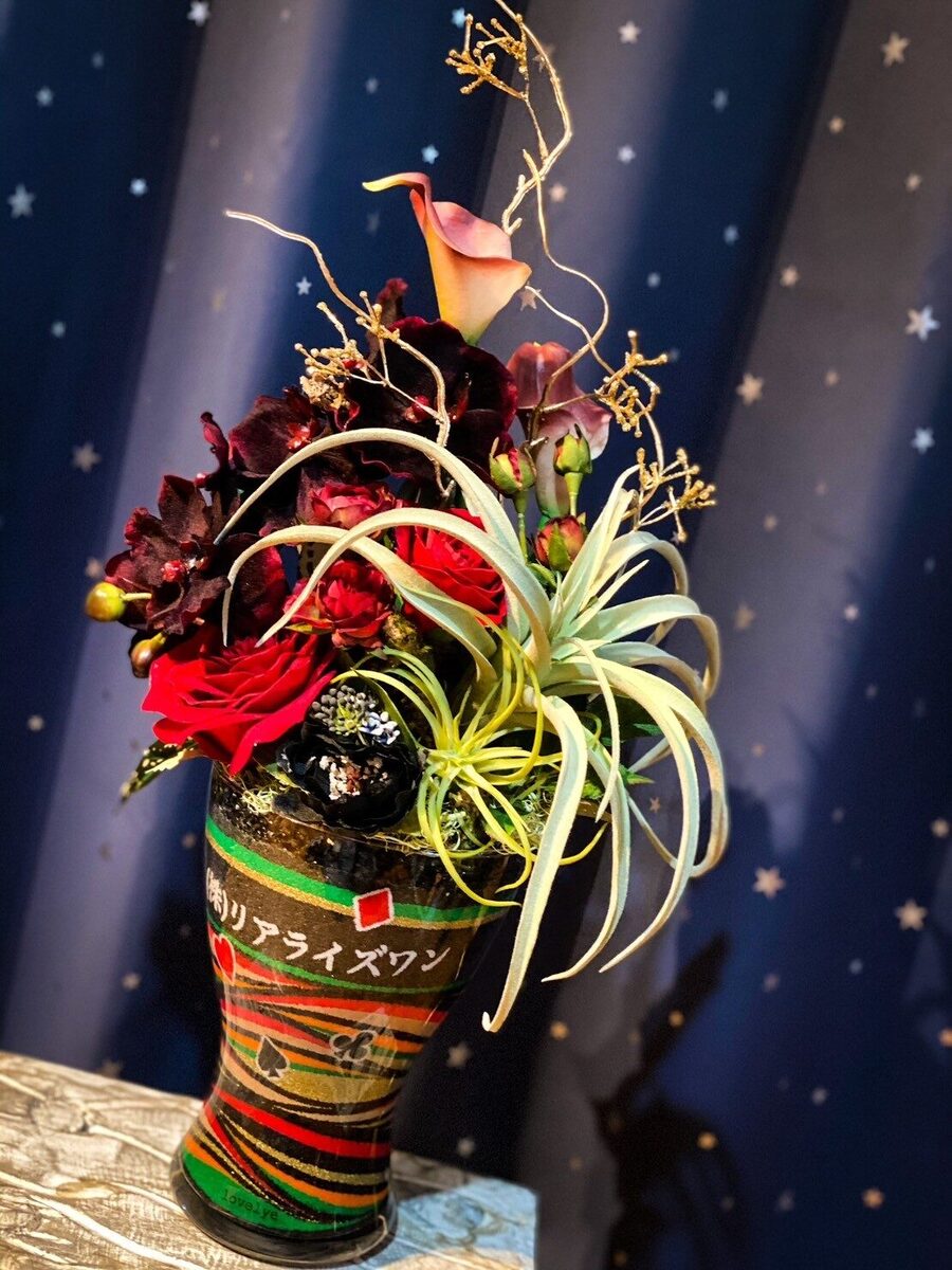 濃紺を背景にしたサンドアート。赤と緑の花をあしらった作品