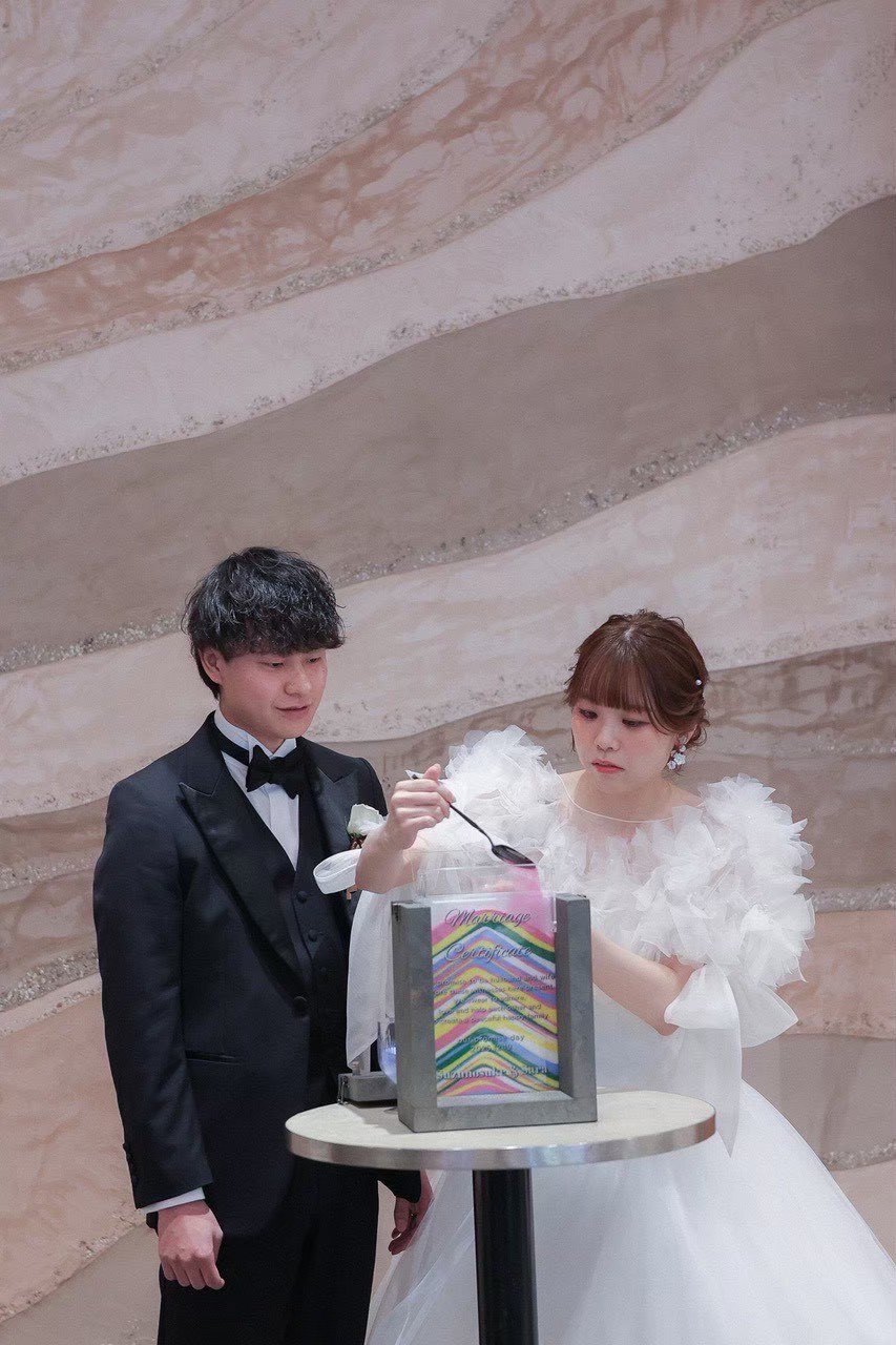完成したサンドセレモニーの結婚証明書の前に立つ新郎新婦